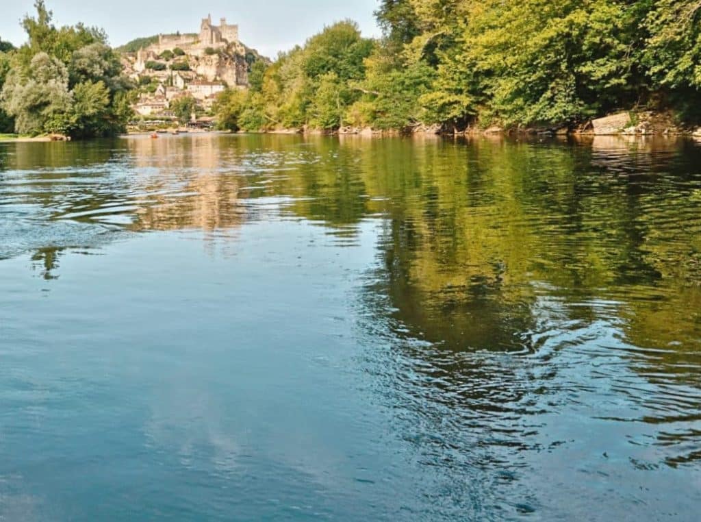Rivière avec château et forêt en arrière-plan.