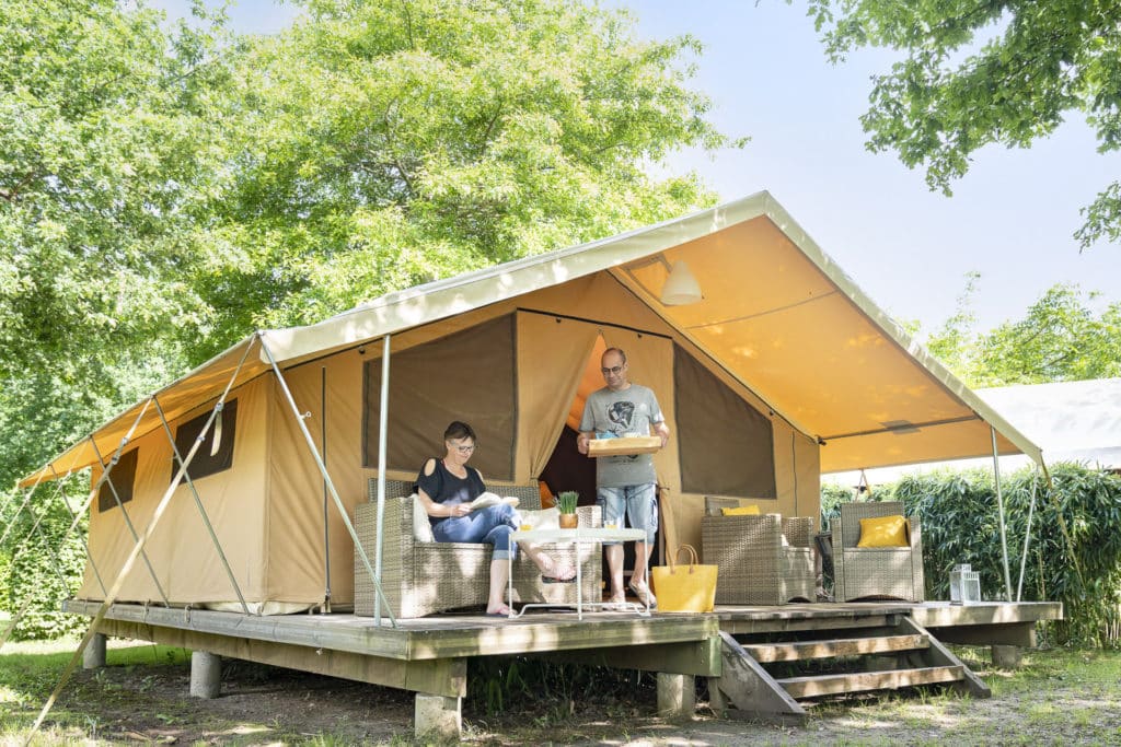 Couple profitant d'une tente glamping ensoleillée.